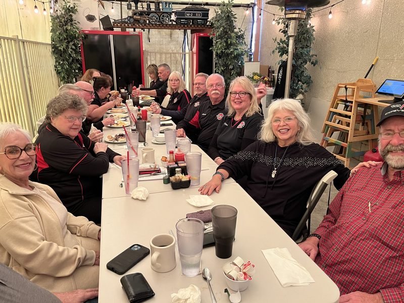 Guests smiling around a long table at a Red Caboose Café gathering