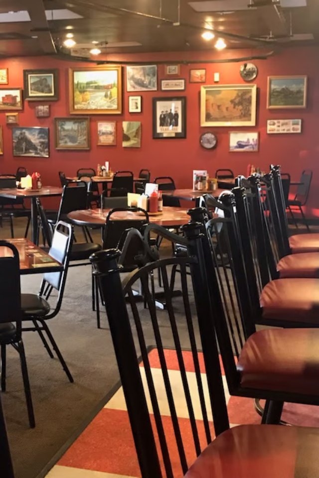 Red dining room walls lined with framed railroad artwork