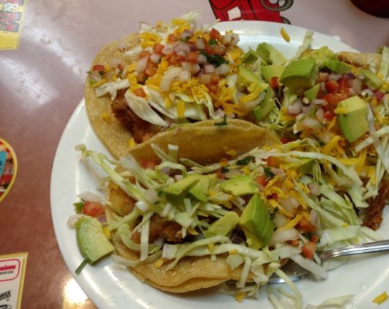 Three fish tacos with cabbage, pico de gallo and avocado